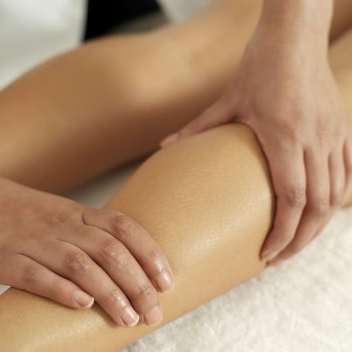 Deep tissue massage therapy being performed on a woman's leg.