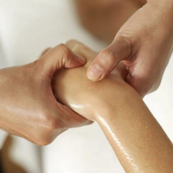 Close-up of a hand receiving a massage, with another hand applying pressure on a thumb, all glistening with oil, reminiscent of the soothing techniques used in a hot stone massage session in Ottawa, Trigger Point Massage