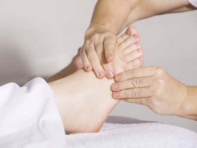 Hands giving a soothing foot massage, with the foot resting on a plush white towel—experience the best of massage therapy in Ottawa.